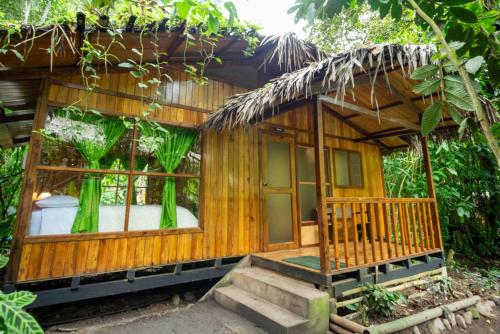 a small wooden house with a porch in the forest at Mindo Lago Hotel Destino in Mindo