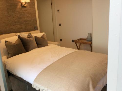 um quarto com uma cama com lençóis brancos e uma mesa em Tigh Beag em Oban