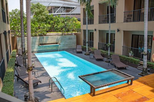 an outdoor swimming pool with chairs and a building at The Cottage Suvarnabhumi in Lat Krabang