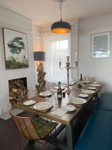 a dining room table with chairs and a long table with glasses at Beautiful 4 Bed Beach House in Pevensey