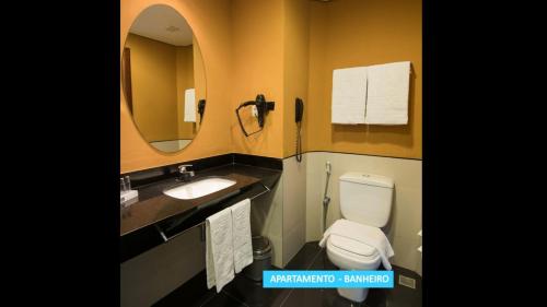 a bathroom with a toilet, sink and mirror at Vila Galé Resort Cumbuco - All inclusive in Cumbuco