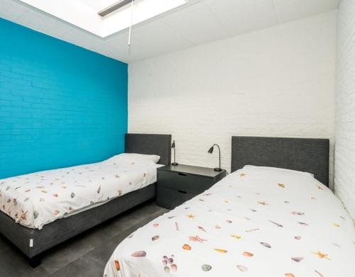 1 dormitorio con 2 camas y pared azul en Appartement Bru 251, en Bruinisse