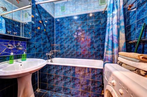 een blauw betegelde badkamer met een wastafel en een bad bij Three-room apartment near Ocean Plaza in Kiev