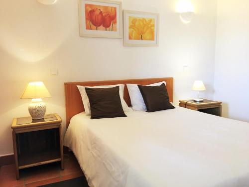 a bedroom with a large bed with two lamps on tables at Apartamento T1 em Lagos com piscina e garagem in Lagos