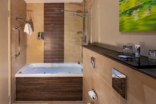 a bathroom with a bath tub and a shower at Mercure Milton Keynes Hotel in Milton Keynes