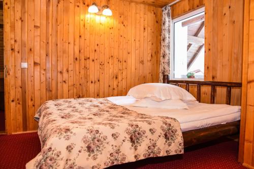 a bed in a wooden room with a window at Colț Viu Cabana in Bran