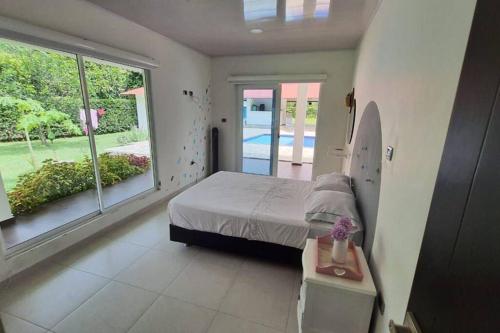 sypialnia z łóżkiem i dużym oknem w obiekcie Casa quinta Las Palmas w mieście Villavicencio