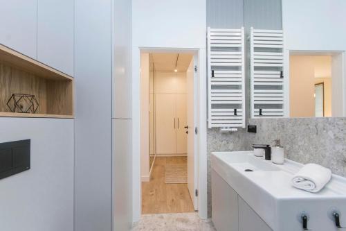 a white bathroom with a sink and a mirror at Margo Rentyear Apartments in Gdańsk