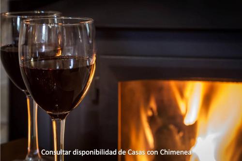 two glasses of wine in front of a fireplace at Complejo Turístico Las Cañadas Casas de Campo- Actividades Gratuitas Todos los Fines de Semana in Baños de Montemayor