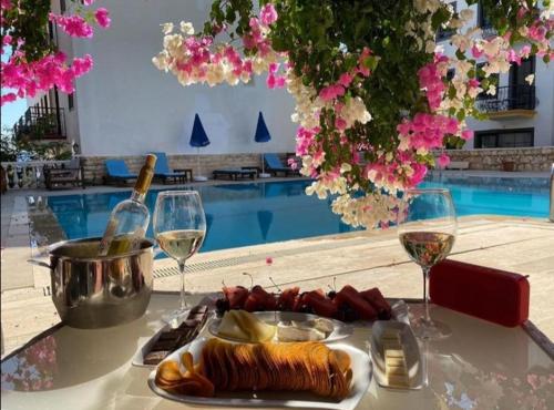a table with a plate of food and glasses of wine at Sevgi Hotel Kalkan in Kalkan