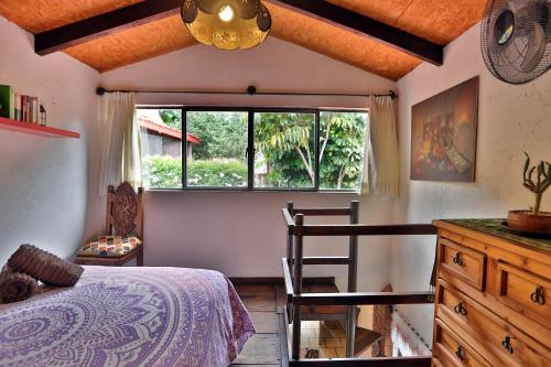 ein Schlafzimmer mit einem Bett, einem Fenster und einem Stuhl in der Unterkunft Majikal B&B - Cabañita in Cholula de Rivadavia