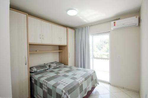 Habitación pequeña con cama y ventana en Condomínio Bromélias - APT 2 QUARTOS, en Bombinhas