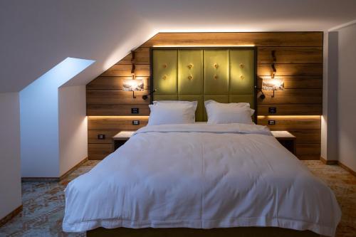 a bedroom with a large white bed with two lamps at Hotel Belmont & Spa in Sinaia
