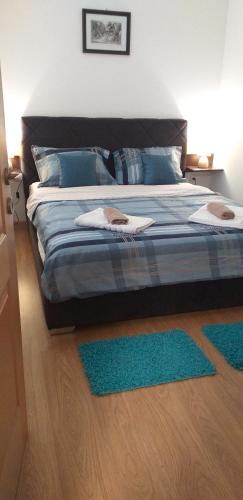 een slaapkamer met een bed met blauwe kussens en groene tapijten bij Apartman Golubovic in Veliko Gradište