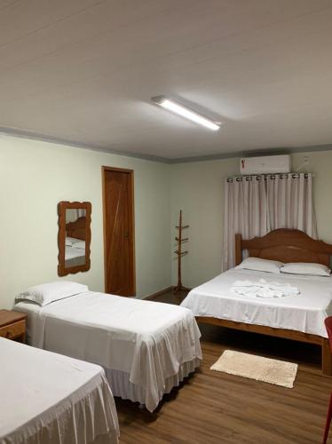 a bedroom with two beds and a cross on the wall at Raludi Hotel in Barcarena