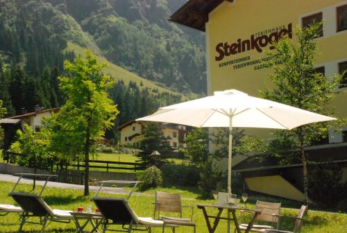 a table and chairs with an umbrella in front of a building at Pension Steinkogel in Sankt Leonhard im Pitztal
