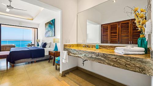 a bathroom with a sink and a bed in a room at Marboka Hotel & Suites in Puerto Vallarta
