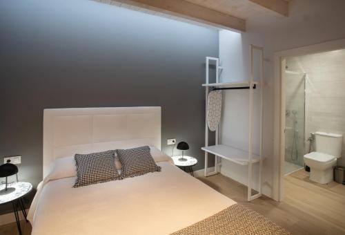 a bedroom with a large white bed and a bathroom at Apartamentos Hondarmendi in Guernica y Luno