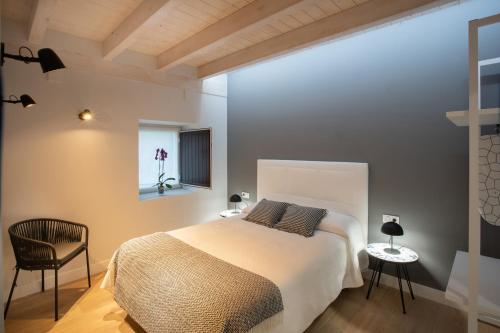 a bedroom with a bed and a chair and a window at Apartamentos Hondarmendi in Guernica y Luno