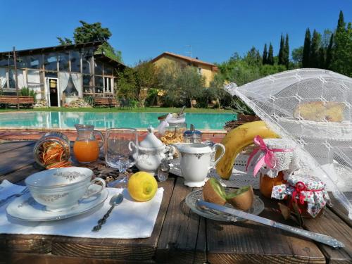 einen Tisch mit einem Frühstück mit Tee und Obst und einem Sonnenschirm in der Unterkunft Podere Piandarca in Terranuova Bracciolini