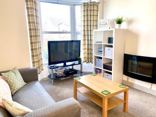 a living room with a couch and a tv and a table at Hiraeth Môn in Menai Bridge