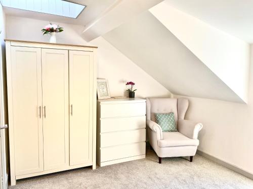 a room with a white cabinet and a chair at Hiraeth Môn in Menai Bridge
