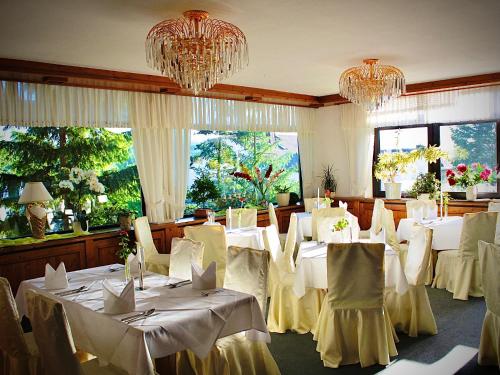 a dining room with white tables and chairs and chandeliers at Meister BÄR HOTEL Frankenwald in Berg