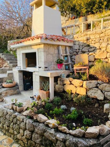 a garden with a fireplace in a stone wall at Mala Cele in Podgora
