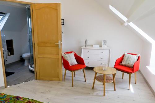 una habitación con dos sillas rojas y una mesa en Band of Brothers House, en Sainte-Marie-du-Mont