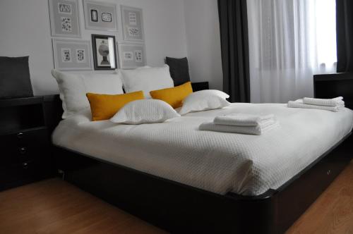 a black and white bed with yellow pillows on it at La Pausa suite Prijepolje in Prijepolje