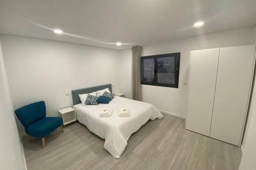 ein Schlafzimmer mit einem Bett und einem blauen Stuhl in der Unterkunft Barcelos Views T3 in Barcelos