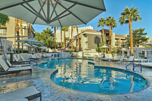 a pool at a resort with chairs and an umbrella at Desert Rose Resort in Las Vegas
