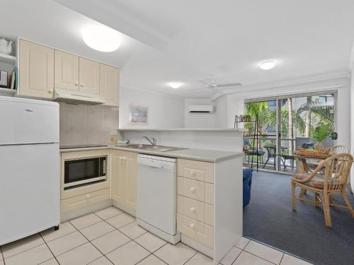 a kitchen with white appliances and a dining room at The Burlington Holiday Apartments in Maroochydore