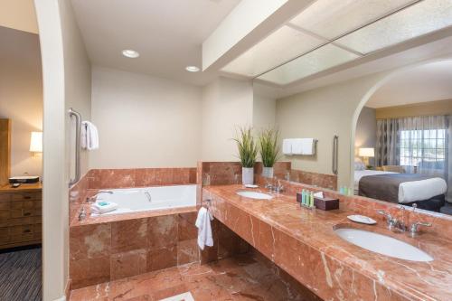 - Baño con 2 lavabos, bañera y cama en The Legacy Golf Resort, en Phoenix