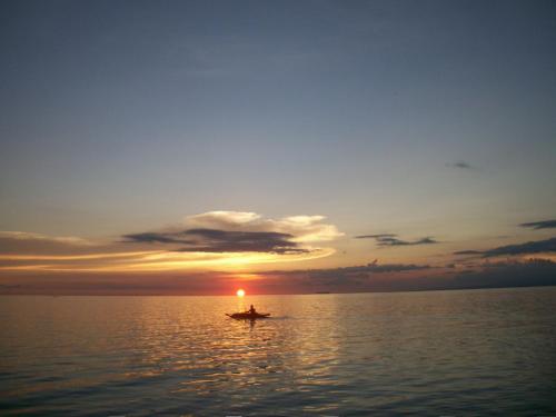 a person in a boat on the water at sunset at Tori's Backpacker's Paradise in Siquijor