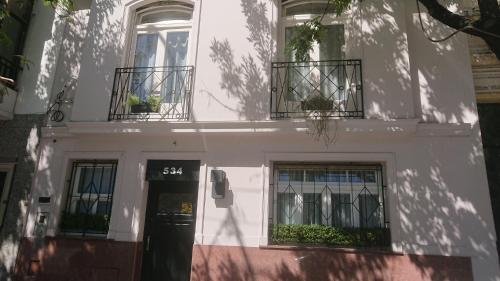 a white building with two balconies and a door at 534 Petit San Telmo - Studio & Suites in Buenos Aires