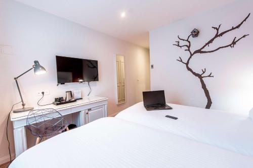 1 dormitorio con cama y escritorio con ordenador portátil en Best Western Plus Au cheval Blanc à Mulhouse, en Baldersheim