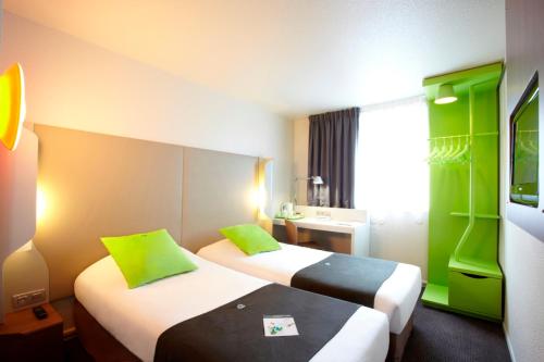 Cette chambre d'hôtel comprend 2 lits avec des touches de vert. dans l'établissement Campanile Paris Est - Pantin, à Pantin