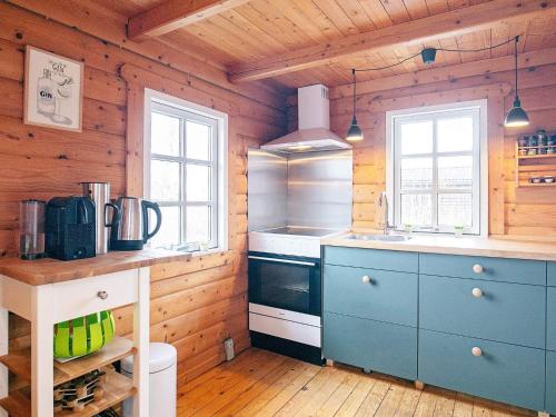 uma cozinha com armários azuis numa cabina de madeira em 4 person holiday home in Assens em Assens