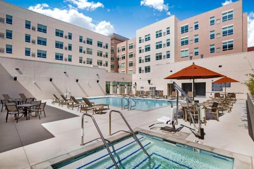 a hotel pool with tables and chairs and an umbrella at Hyatt House LA - University Medical Center in Los Angeles