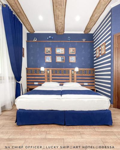 1 dormitorio con 1 cama grande y paredes azules en Lucky Ship Art Hotel en Odesa