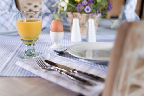 un tavolo con un uovo e un bicchiere di succo d'arancia di Gasthaus und Pension "Zum Hauenden Schwein" a Wörlitz