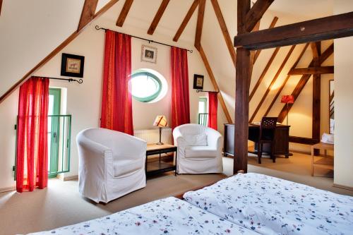 a bedroom with a bed and two chairs at Gasthaus und Pension "Zum Hauenden Schwein" in Wörlitz