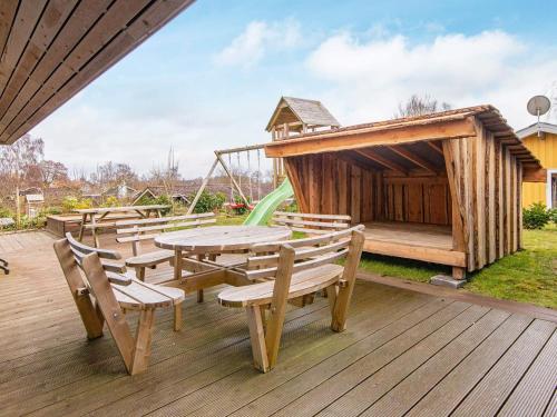 a wooden deck with a picnic table and a playground at 8 person holiday home in Hejls in Hejls