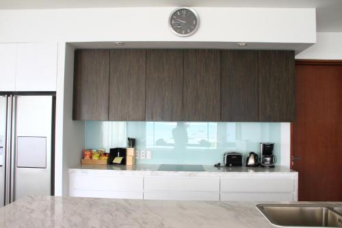 a kitchen with white cabinets and a clock on the wall at The Ocean Villas Managed by The Ocean Resort in Da Nang