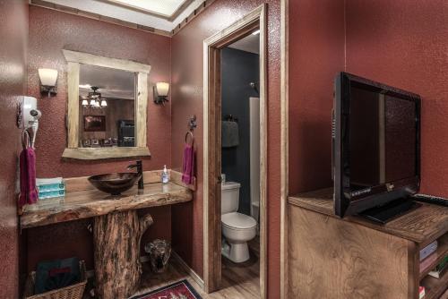 a bathroom with a sink and a toilet and a television at Shadow Mountain Lodge and Cabins in Ruidoso