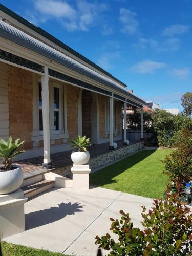 une maison avec des colonnes blanches et de l'herbe verte dans l'établissement Semaphore Sea Breeze-Family Beach-Heated Plunge Pool Holiday House 4 brm 2 bath, à Semaphore