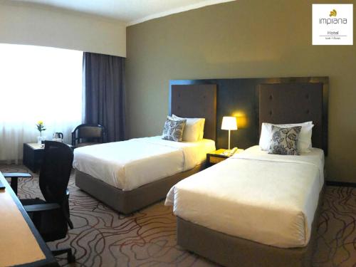 a hotel room with two beds and a window at Impiana Hotel Ipoh in Ipoh