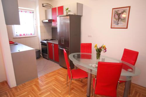 cocina con mesa de cristal y sillas rojas en Apartment Marina, en Trogir