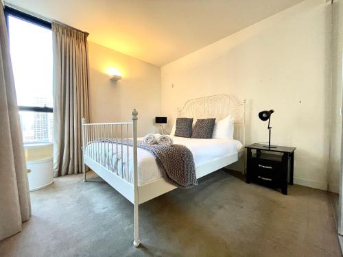 a bedroom with a white bed and a window at ReadySet Apartments on Spencer in Melbourne
